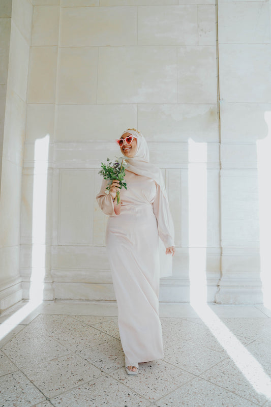 Robe en satin russe couleur nude rosé avec croisé à la taille.  Manches longues évasées